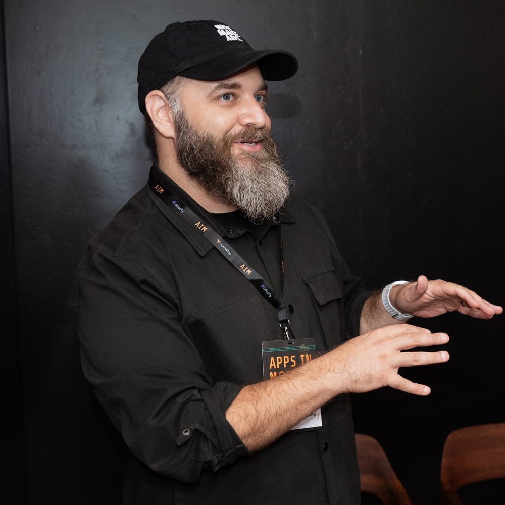 Barry Hott talking with his hands at a conference, wearing a Just Make Ads cap and an event lanyard
