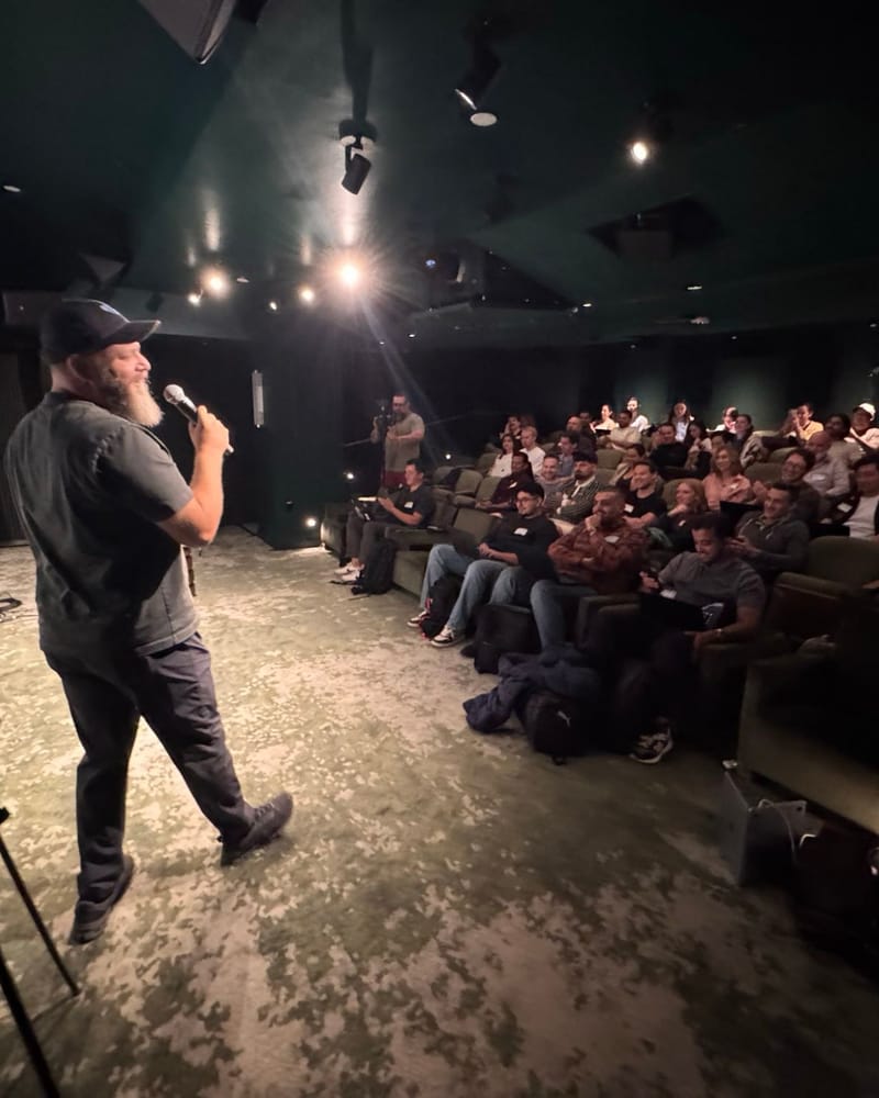 Barry Hott talking into a microphone to a full room of smiling attendees